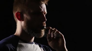 Adam elektronik sigara içiyor ve çok fazla duman exhales. Siyah arka plan
