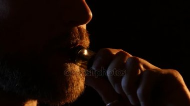 Adam karanlık bir odaya duman exhales. Siyah arka plan. Yakın çekim
