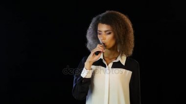 Kadın bir elektronik sigara karanlık bir odada duruyor. Siyah arka plan