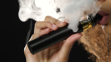 Dudaklar bir kızın Afro-Amerikan görünüm bir vaping içiyor. Siyah arka plan. Yakın çekim