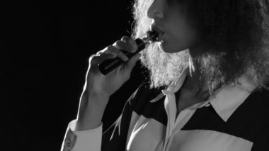 Dudaklar bir kızın Afro-Amerikan görünüm elektronik sigara içiyor. Siyah arka plan. Yakın çekim