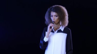 Kız Afro-Amerikan görünüm elektronik sigara içiyor. Siyah arka plan