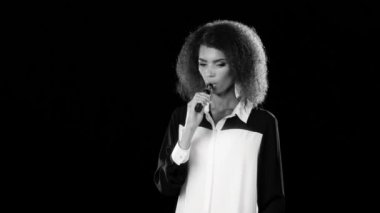 Kız Afro-Amerikan görünüm elektronik sigara içiyor. Siyah arka plan