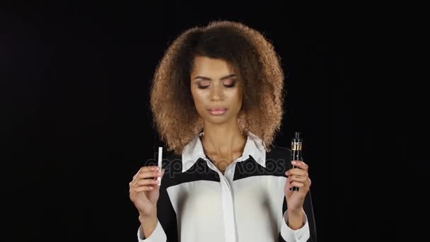 Kız elektronik sigara ve sıradan bir arasında bir seçimdir. Siyah arka plan — Stok video