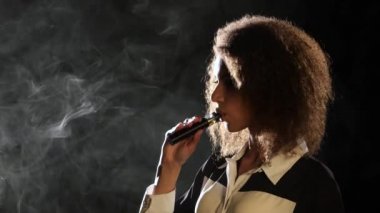 Kız bir vape içiyor, lezzetli bir aroma seviyor. Siyah arka plan