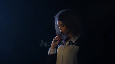 Kız inhales ve bir e-sigara dumanı exhales. Siyah arka plan