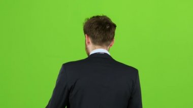 Adam sokakta yürüyor, onun cep ve dalgalar elini koyar. Yeşil ekran. Arkadan Görünüm