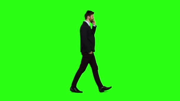 Geschäftsmann geht die Straße hinunter, steckt die Hand in die Tasche und telefoniert. Green Screen. Zeitlupe — Stockvideo