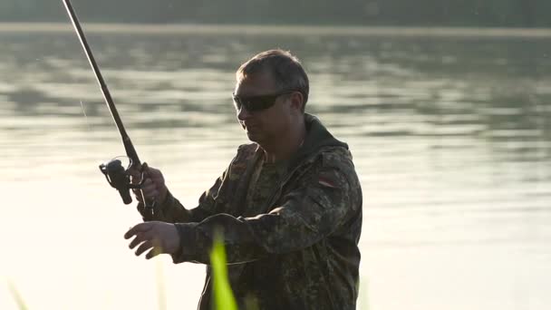 Man clings a bait to a fishing rod, he wants to catch fish. Slow motion — Stock Video