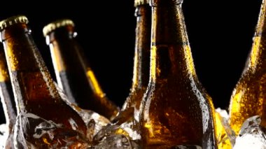Buz parçalar halinde dönmeye koyu bira şişeleri. Siyah arka plan. Yakın çekim