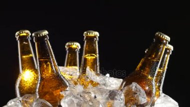 Buz parçalar halinde dönmeye koyu bira şişeleri. Siyah arka plan. Yakın çekim