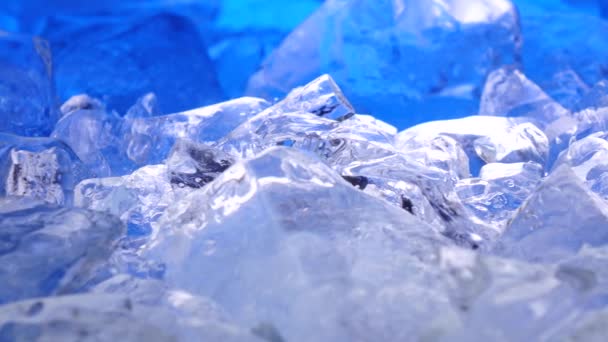 Pezzi di ghiaccio si trova sul tavolo, illuminazione blu si trova splendidamente sopra frammenti. Da vicino. — Video Stock