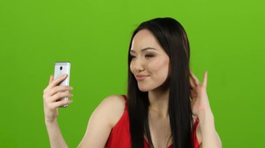 Asyalı kız selfie yapar, o kameraya bakarken gülümsüyor. Yeşil ekran