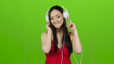Neşeli ve enerjik müzik kulaklık kız dinler. Yeşil ekran. Ağır çekim