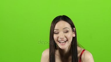 Asyalı kız eğleniyor ve güzel gülümsemesi yüksek sesle gülüyor. Yeşil screenc