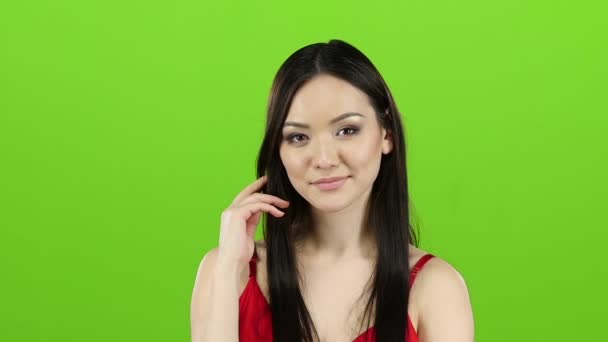 Meisje in een rode jurk flirt, stuurt kussen en glimlacht. Groen scherm. Slow motion — Stockvideo