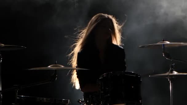Meisje is kicks van het bespelen van drums, energieke muziek spelen. Zwarte rook achtergrond. Silhouet — Stockvideo
