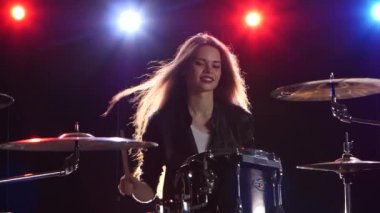 Kız davul oynuyor. Siyah arka plan. Arkadan kırmızı mavi ışık