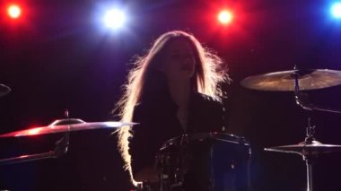 Kız davul oynuyor. Siyah arka plan. Arkadan kırmızı mavi ışık