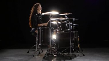 Baterist kız enerjik müzik, o gülümsüyor çalmaya başlar. Siyah arka plan