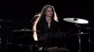 Baterist kız enerjik müzik, o gülümsüyor çalmaya başlar. Siyah arka plan. Ağır çekim