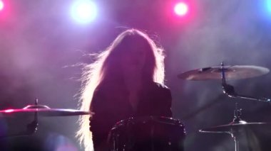 Davulcu profesyonel bir müzik aleti çalıyor. Siyah duman arka plan. Arkadan kırmızı mavi ışık. Ağır çekim