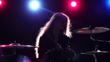 Kız davul oynuyor. Siyah arka plan. Arkadan kırmızı mavi ışık. Ağır çekim