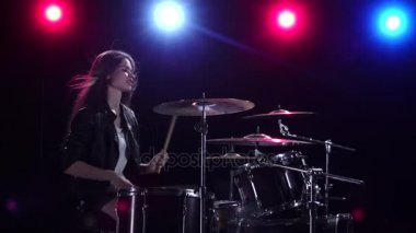 Kız davul oynuyor. Siyah arka plan. Arkadan kırmızı mavi ışık. Yan görünümü. Ağır çekim