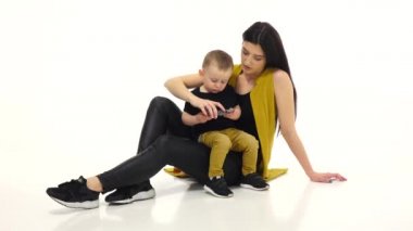 Anne ve çocuk bir smartphone cep telefonu ile çizgi film izliyor. Beyaz arka plan