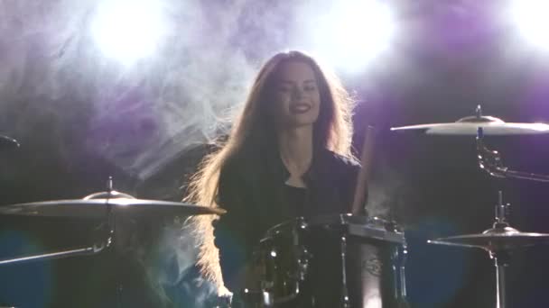 Барабанщик играет на барабанах на рок-концерте. Черный дым фон. Свет сзади — стоковое видео