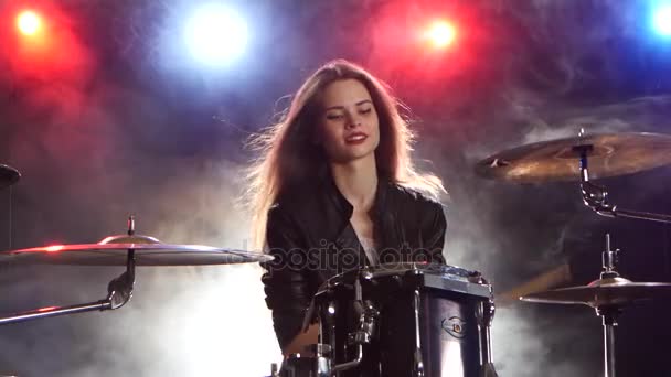 女の子は、ドラムと笑顔を果たしています。黒い煙の背景。後ろから赤い青い光 — ストック動画
