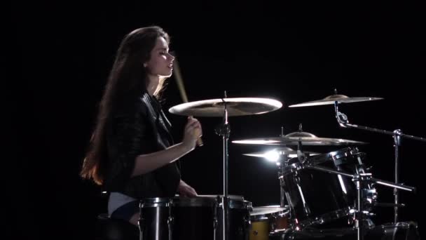 Baterista menina com pauzinhos bate música rítmica. Fundo preto. Vista lateral. Movimento lento — Vídeo de Stock