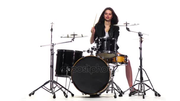 La chica baterista empieza a tocar música enérgica, sonríe. Fondo blanco. Movimiento lento — Vídeos de Stock