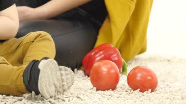 Küçük çocuk annesi yanında dolmalık biber yiyor. Beyaz arka plan. Yakın çekim