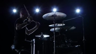 Müzisyen profesyonel müzik davul çalıyor. Siyah arka plan. Yan görünümü. Arka ışık. Siluet. Ağır çekim