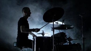 Enerjik müzisyen iyi müzik davul çalıyor. Siyah dumanlı arka plan. Yan görünümü. Siluet. Ağır çekim