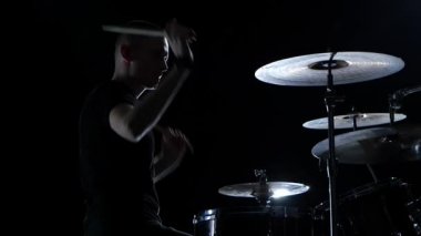 Müzisyen profesyonel olarak iyi müzik sopa kullanma davul çalıyor. Siyah arka plan. Siluet. Ağır çekim