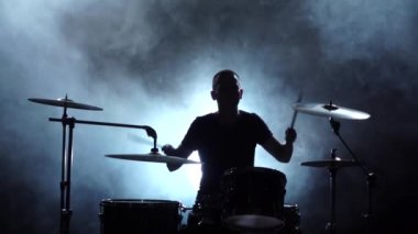 Adam müzik davul çalıyor. Siyah dumanlı arka plan. Siluetleri. Yan görünümü. Ağır çekim