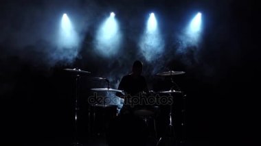 Enerjik müzisyen iyi müzik davul çalıyor. Siyah dumanlı arka plan. Arka ışık. Siluet. Ağır çekim