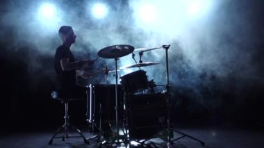 Müzisyen profesyonel olarak iyi müzik sopa kullanma davul çalıyor. Dumanlı arka plan. Siluet. Ağır çekim