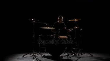 Profesyonel müzisyen müzik sopa yardımıyla davul çalıyor. Siyah arka plan. Siluet