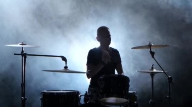 Profesyonel müzisyen müzik sopa yardımıyla davul çalıyor. Dumanlı arka plan. Siluet