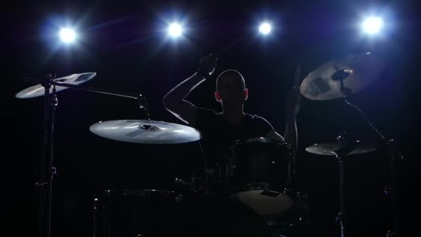 O baterista toca a melodia na bateria energeticamente. Fundo preto. Luz traseira. Silhueta. Movimento lento — Vídeo de Stock