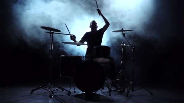 El baterista toca la melodía en la batería con energía. Fondo negro. Silueta. Movimiento lento — Vídeos de Stock