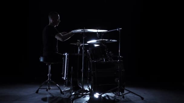 O baterista toca música enérgica no tambor. Fundo preto. Vista lateral. Movimento lento — Vídeo de Stock