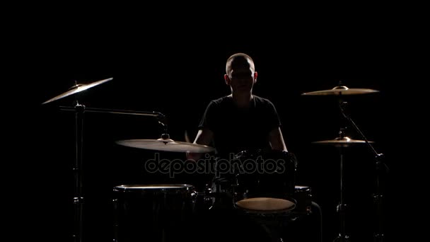 Músico toca profissionalmente boa música na bateria usando paus. Fundo preto. Silhueta — Vídeo de Stock