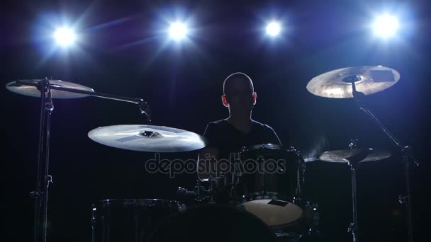 O baterista toca a melodia na bateria energeticamente. Fundo preto. Luz traseira. Silhueta — Vídeo de Stock