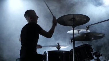 Müzisyen bir melodi üzerinde bateri çalıyor. Siyah duman arka plan. Yan görünümü. Siluetleri