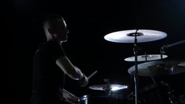 Müzisyen profesyonel olarak iyi müzik sopa kullanma davul çalıyor. Siyah arka plan. Siluet
