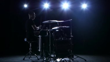 Davulcu melodi enerjik üzerinde bateri çalıyor. Siyah arka plan. Arka ışık. Siluet
